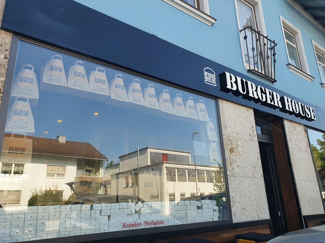 Außenansicht von "Burger House" mit  großem Schaufenster, dekoriert mit "Burger House" ToGo-Tüten.